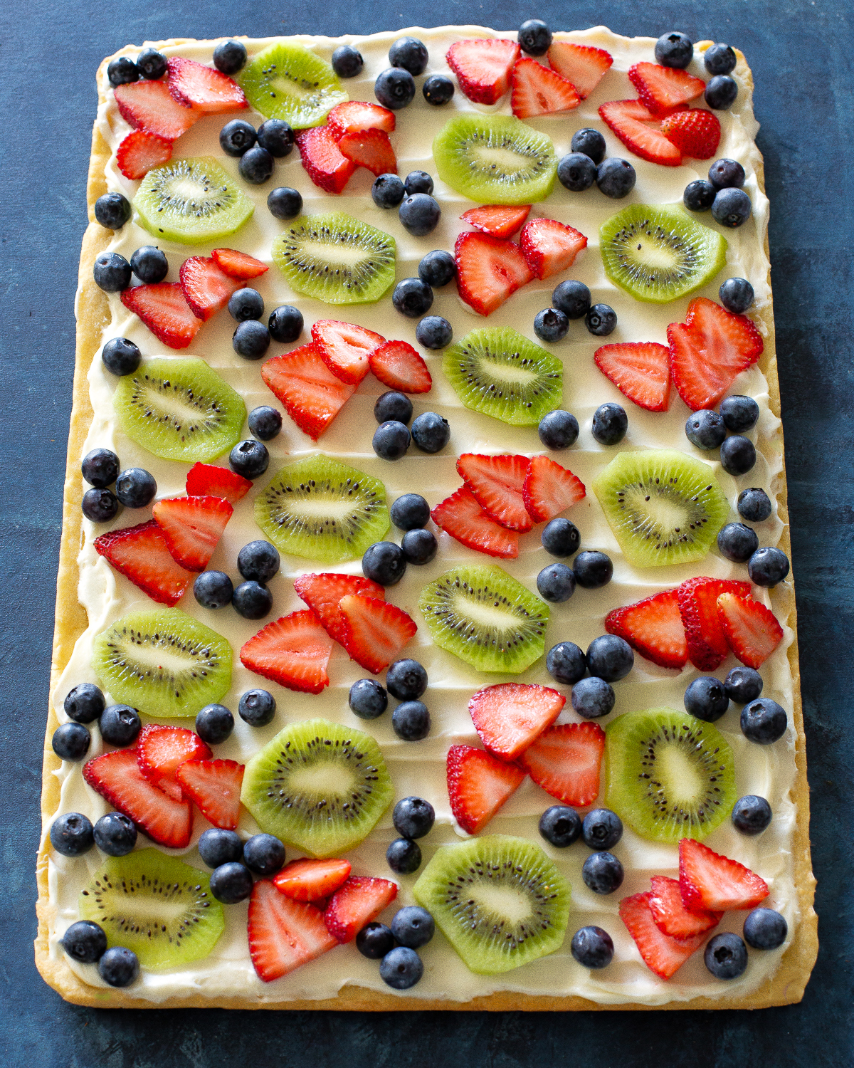 Fruit Pizza is a delicious dessert for a potluck. It starts with a sugar cookie base and a cream cheese frosting topped with assorted fruit. #fruit #pizza #dessert #recipe