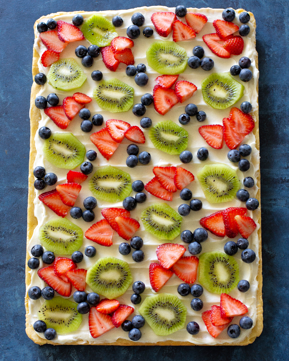 Fruit Pizza is a delicious dessert for a potluck. It starts with a sugar cookie base and a cream cheese frosting topped with assorted fruit. #fruit #pizza #dessert #recipe