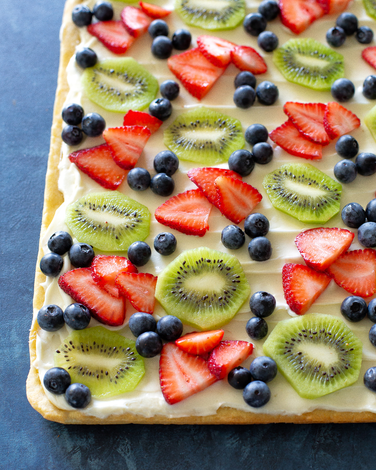 Fruit Pizza is a delicious dessert for a potluck. It starts with a sugar cookie base and a cream cheese frosting topped with assorted fruit. #fruit #pizza #dessert #recipe