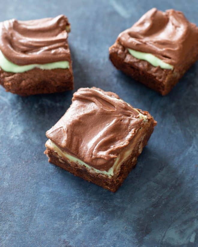 brownies with frosting on a blue board