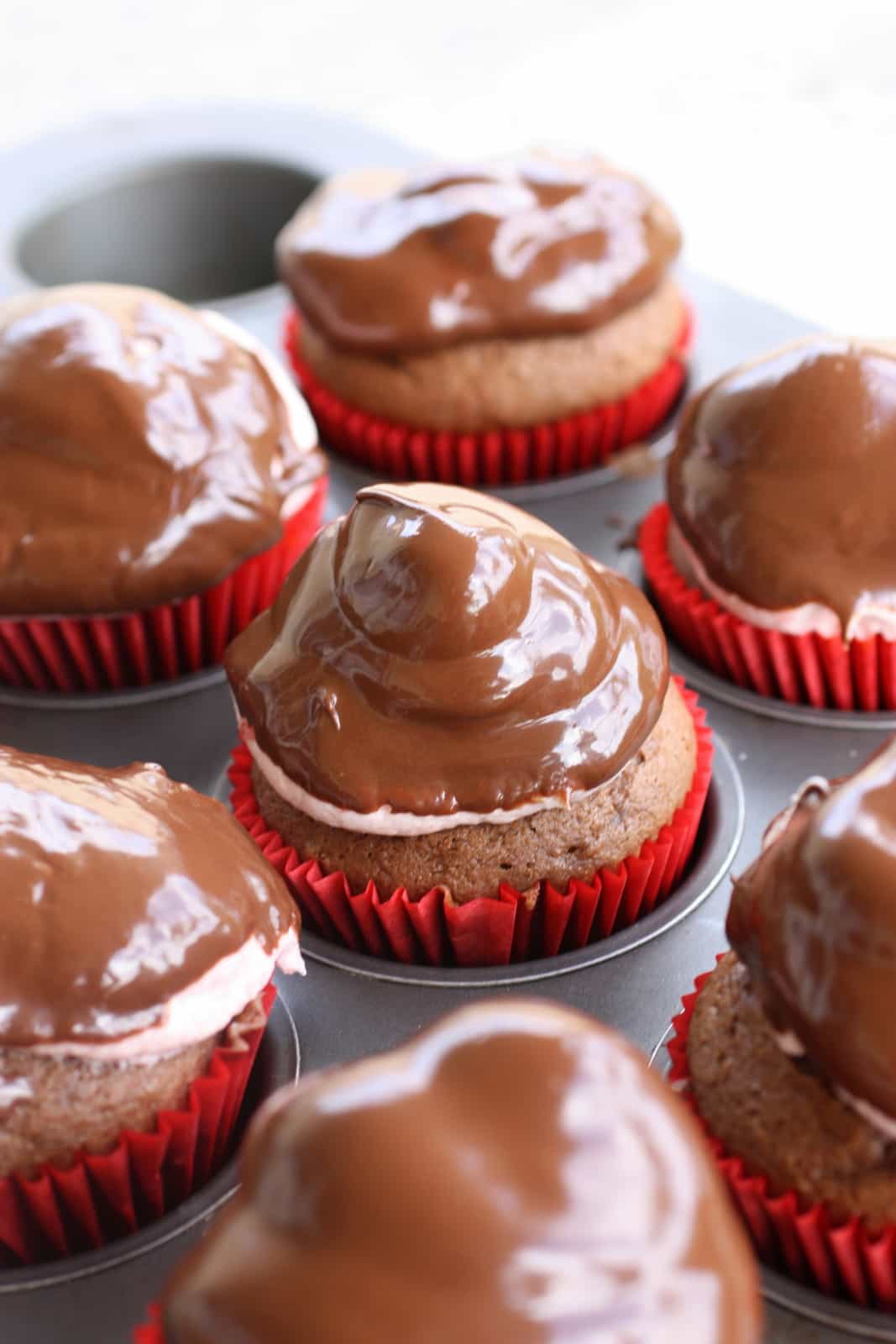 Strawberry Puffcakes - chocolate cupcakes topped with strawberry cream and dipped in chocolate. the-girl-who-ate-everything.com