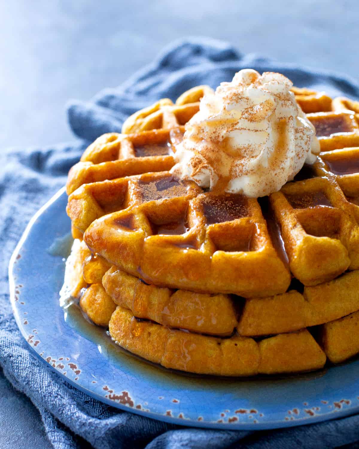pumpkin waffles with whipped cream on a blue plate