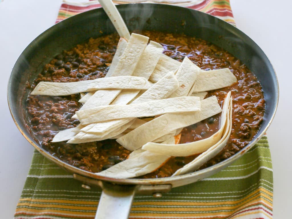 This Easy Beef Burrito Skillet has beef, black beans, salsa, and tortillas all cooked in one skillet. The tortillas turn soft and almost like a dumpling. This tasty dish is done in less than 20 minutes. the-girl-who-ate-everything.com