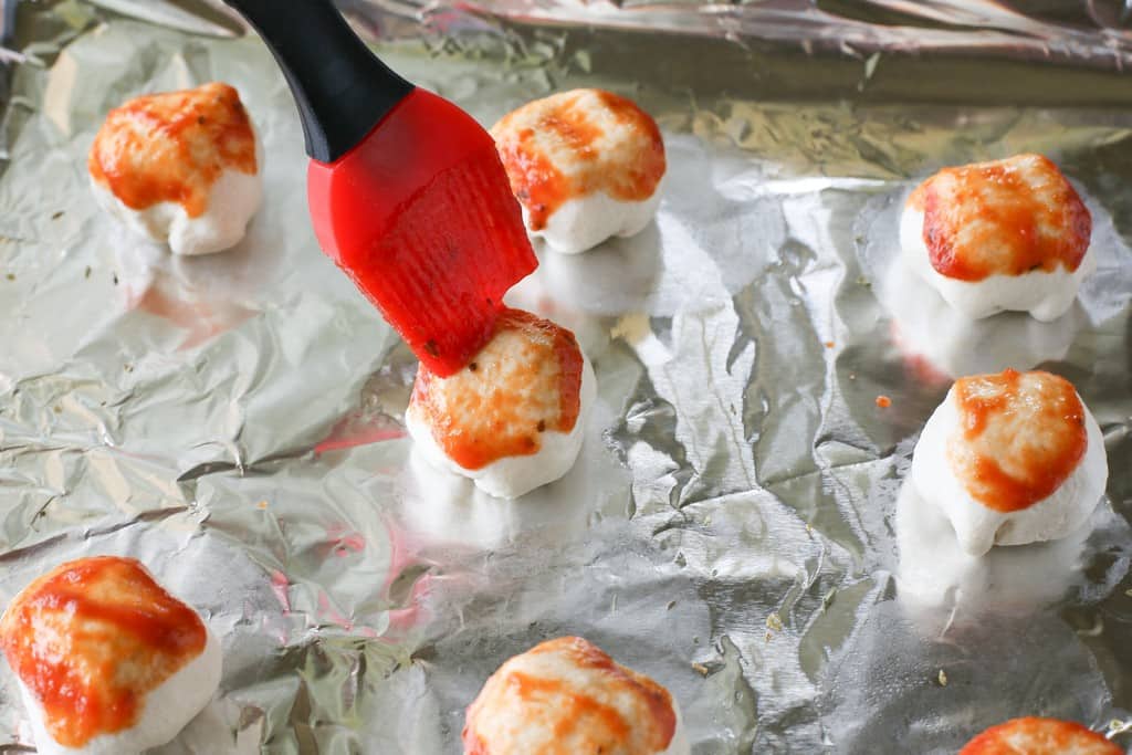 Mozzarella Puffs - dough stuffed with cubes of mozzarella cheese and brushed with pizza sauce. You could also add some pepperoni inside! These are so quick and easy. the-girl-who-ate-everything.com