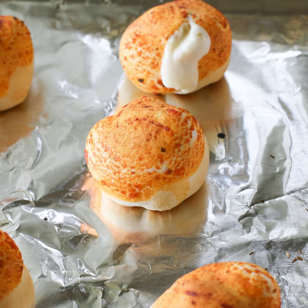 Mozzarella Puffs - dough stuffed with cubes of mozzarella cheese and brushed with pizza sauce. You could also add some pepperoni inside! These are so quick and easy. the-girl-who-ate-everything.com