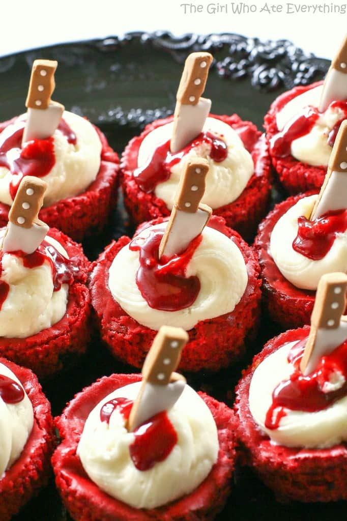Mini Red Velvet Cheesecakes - moist red velvet cheesecake with an Oreo crust. The best recipe I've ever had. Topped with cream cheese for the ultimate indulgence. Add some edible blood for a dramatic Halloween dessert. the-girl-who-ate-everything.com