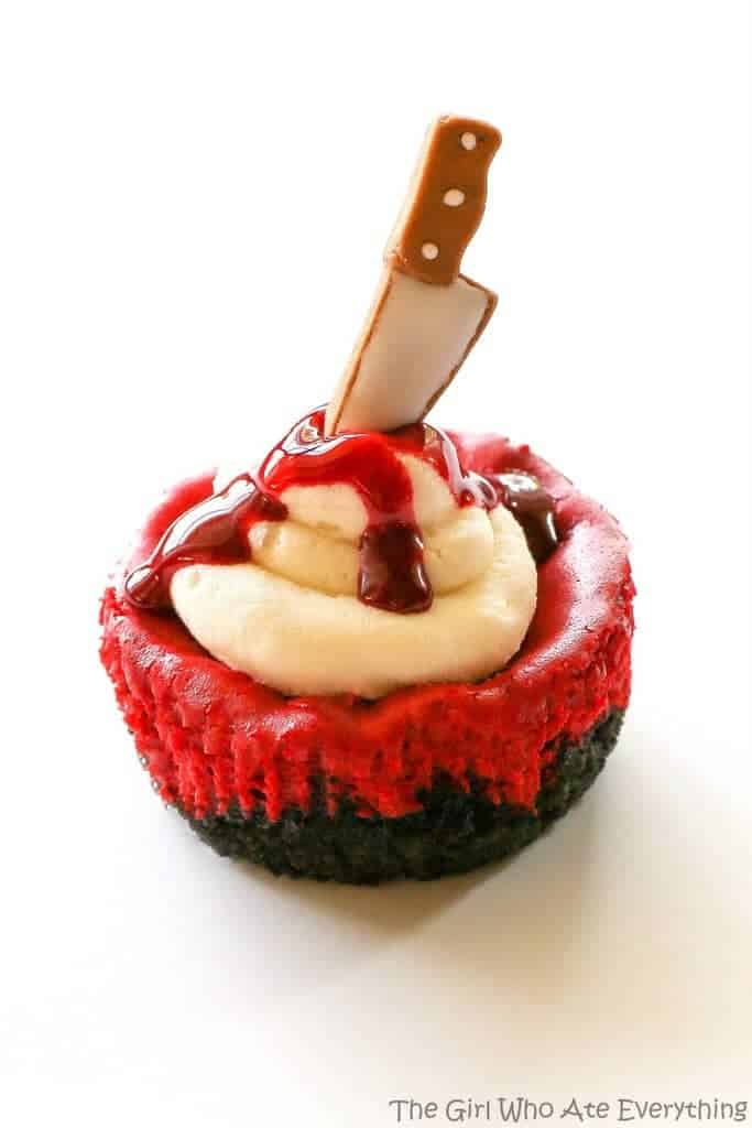 Mini Red Velvet Cheesecakes - moist red velvet cheesecake with an Oreo crust. The best recipe I've ever had. Topped with cream cheese for the ultimate indulgence. Add some edible blood for a dramatic Halloween dessert. the-girl-who-ate-everything.com
