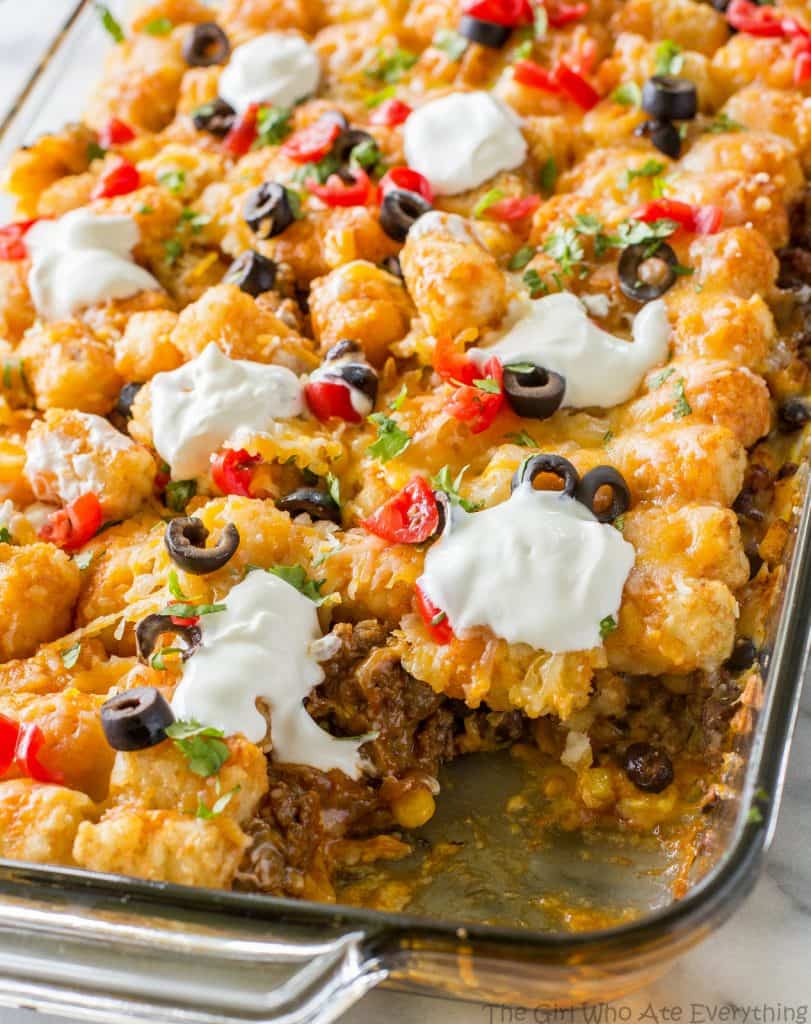 Tater Taco Casserole - A Mexican mixture of taco meat, beans, corn, and cheese topped with tater tots and enchilada sauce. the-girl-who-ate-everything.com