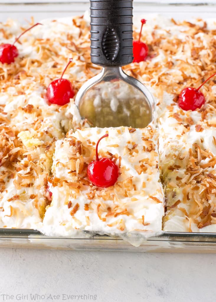 Pina Colada Poke Cake - drizzled with coconut and pineapple and topped with coconut whipped cream and toasted coconut, this cake is the best summer cake out there. the-girl-who-ate-everything.com
