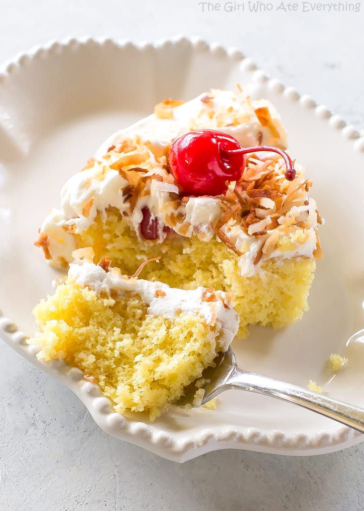 Pina Colada Poke Cake - drizzled with coconut and pineapple and topped with coconut whipped cream and toasted coconut, this cake is the best summer cake out there. the-girl-who-ate-everything.com