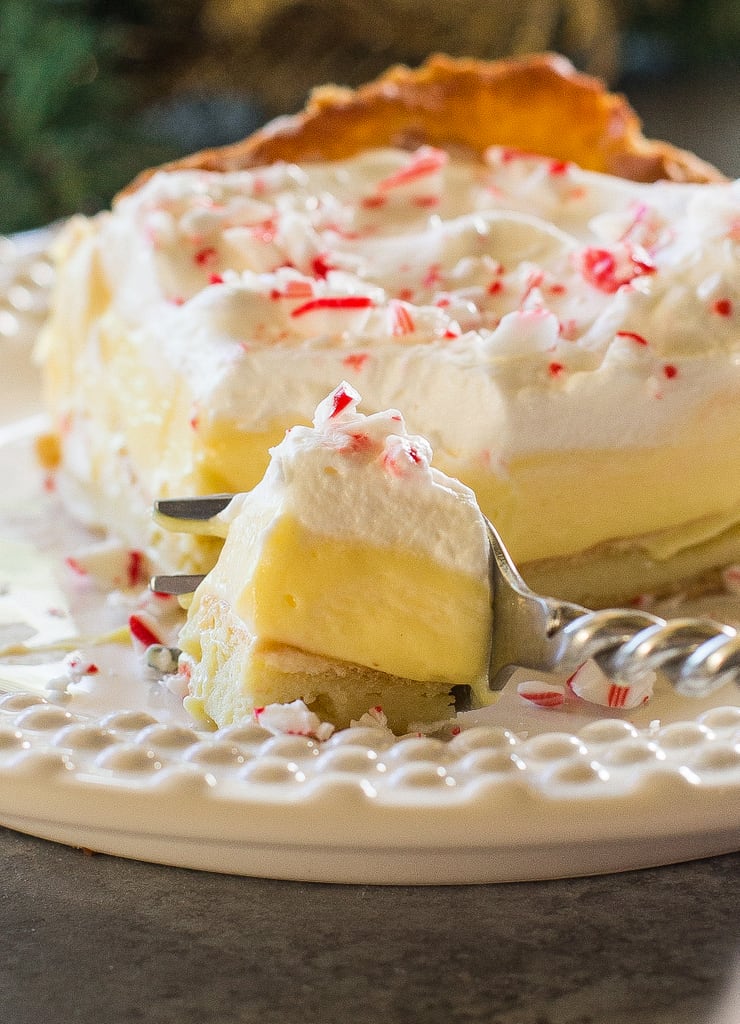 This Eggnog Éclair Cake is a unique holiday dessert with a cream puff crust, creamy eggnog layer, and topped with fresh cream and crushed peppermint candies.