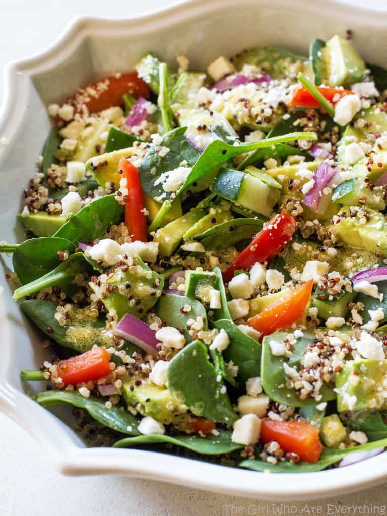 Spinach Quinoa Salad - full of rich healthy foods like cucumber, red bell pepper, avocado, and onion. This recipe is topped with a lemon dijon vinaigrette. the-girl-who-ate-everything.com