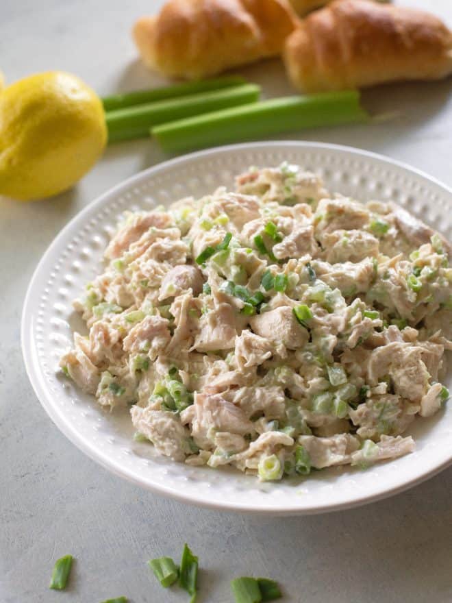 chicken salad on a white plate with a lemon